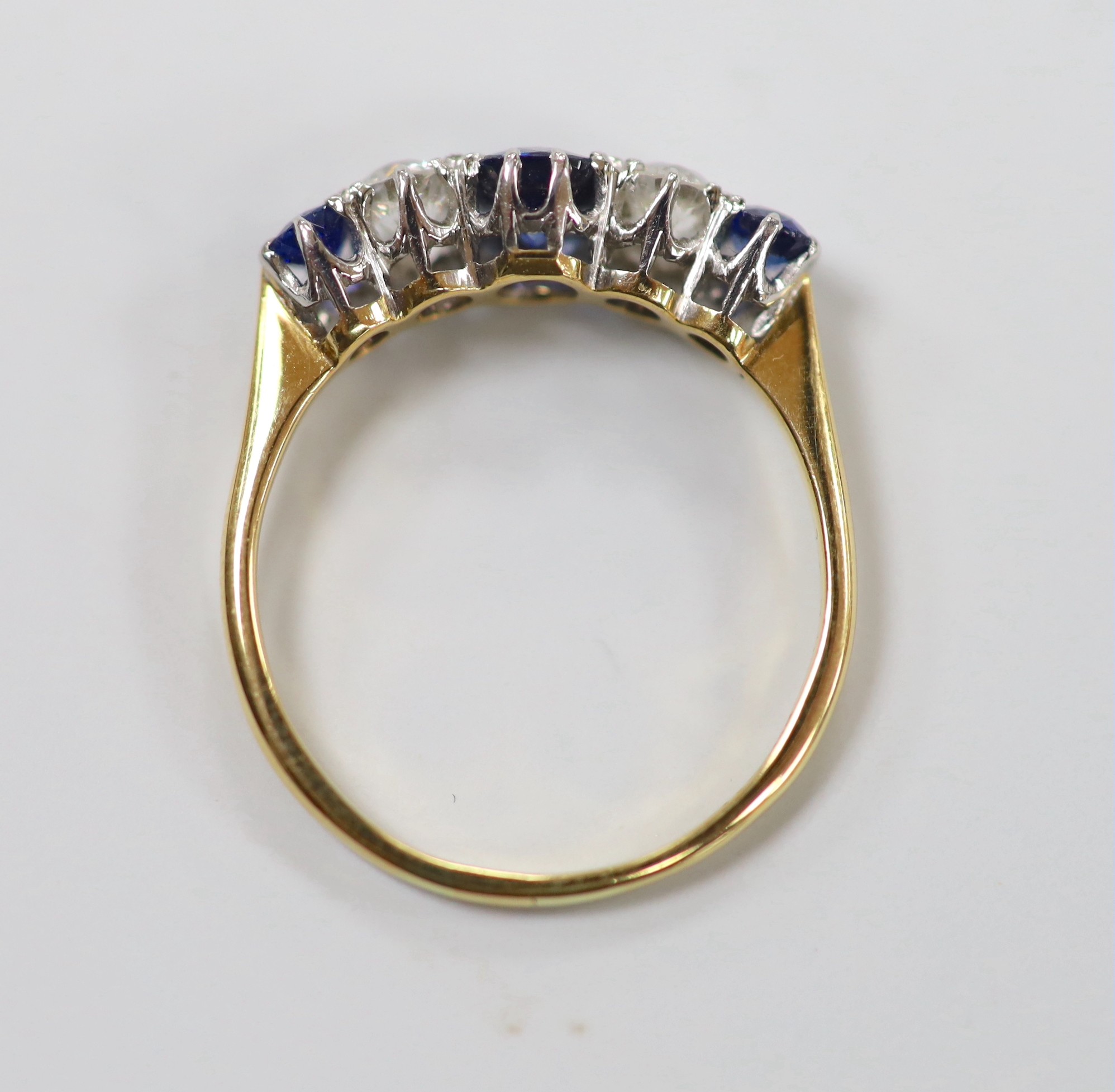 An 18ct, three stone sapphire and two stone diamond set half hoop ring, size P, gross weight 2.7 grams.